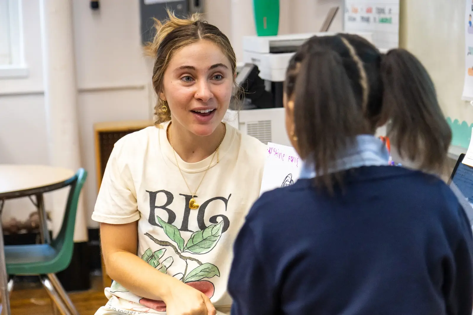 Adult volunteer engaging enthusiastically with a student in classroom