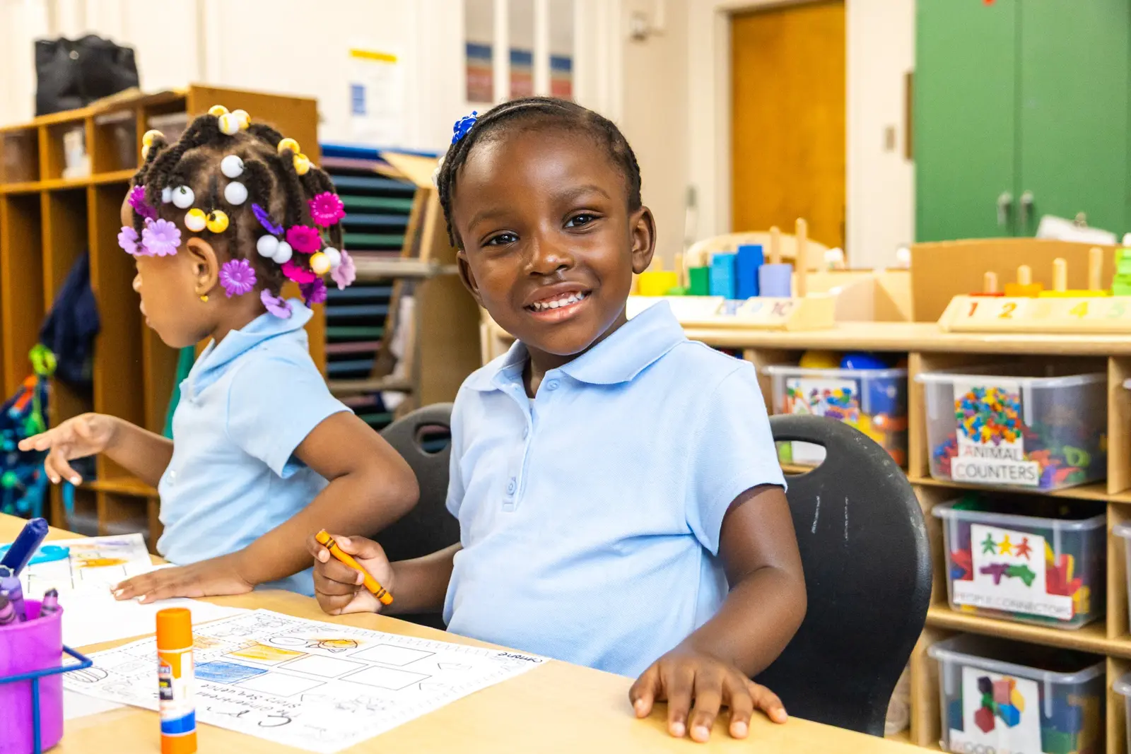 Smiling young student holding a crayon during classroom activity