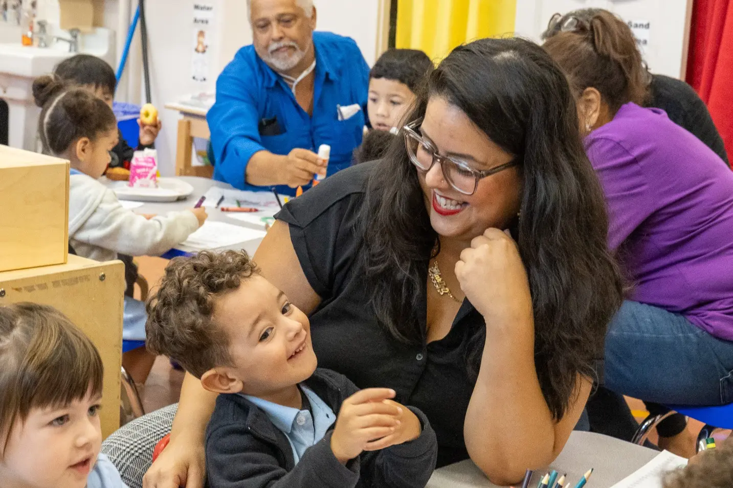 Teacher smiling and engaging with a young student in classroom