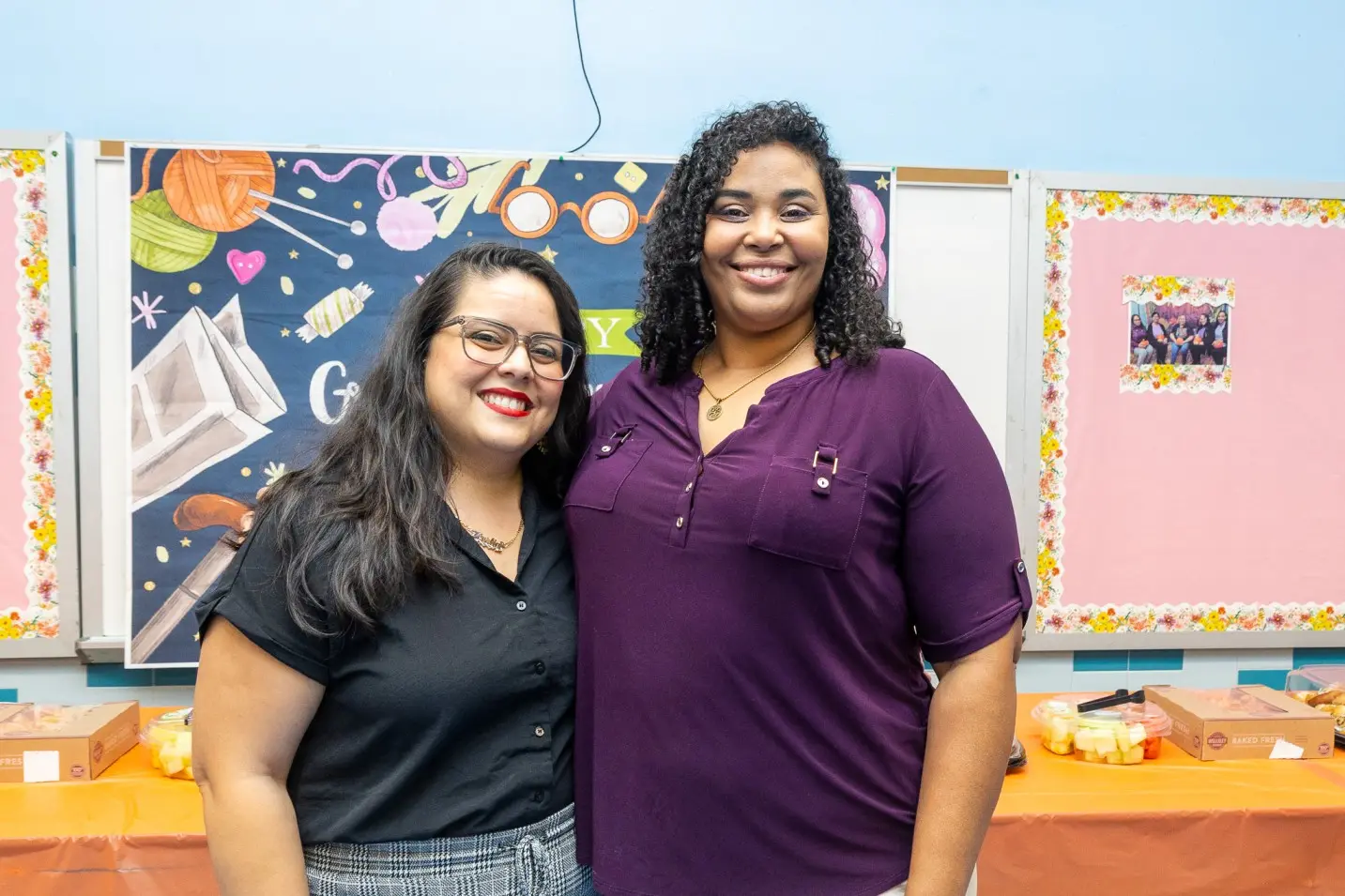 Two smiling staff members posing together at a school event