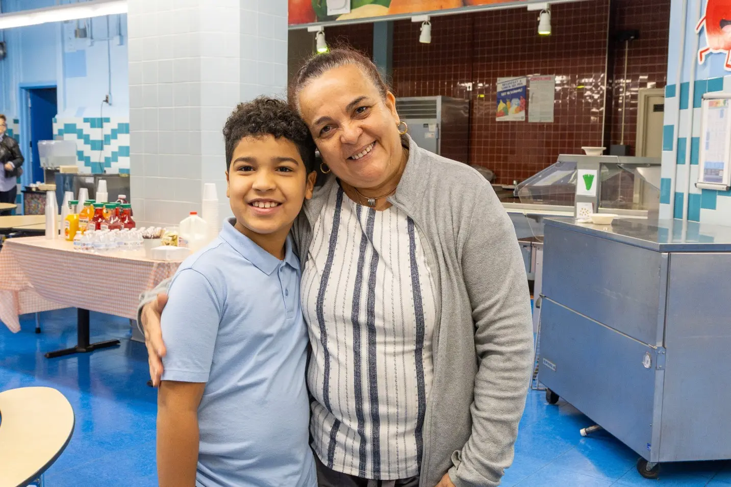 Student and adult smiling together in school cafeteria