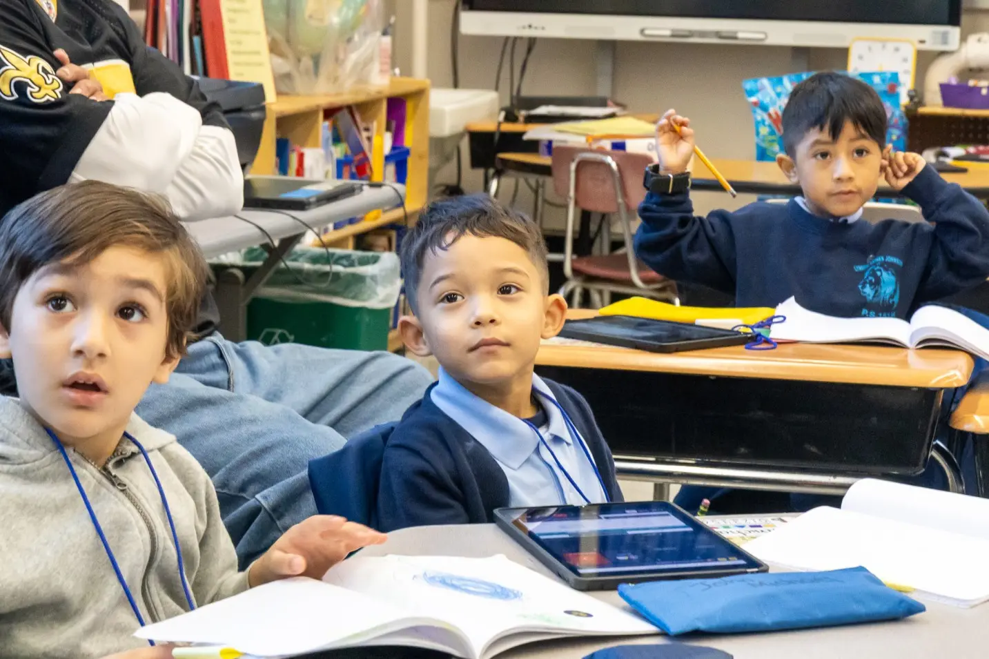 Three elementary students attentively listening during a classroom lesson