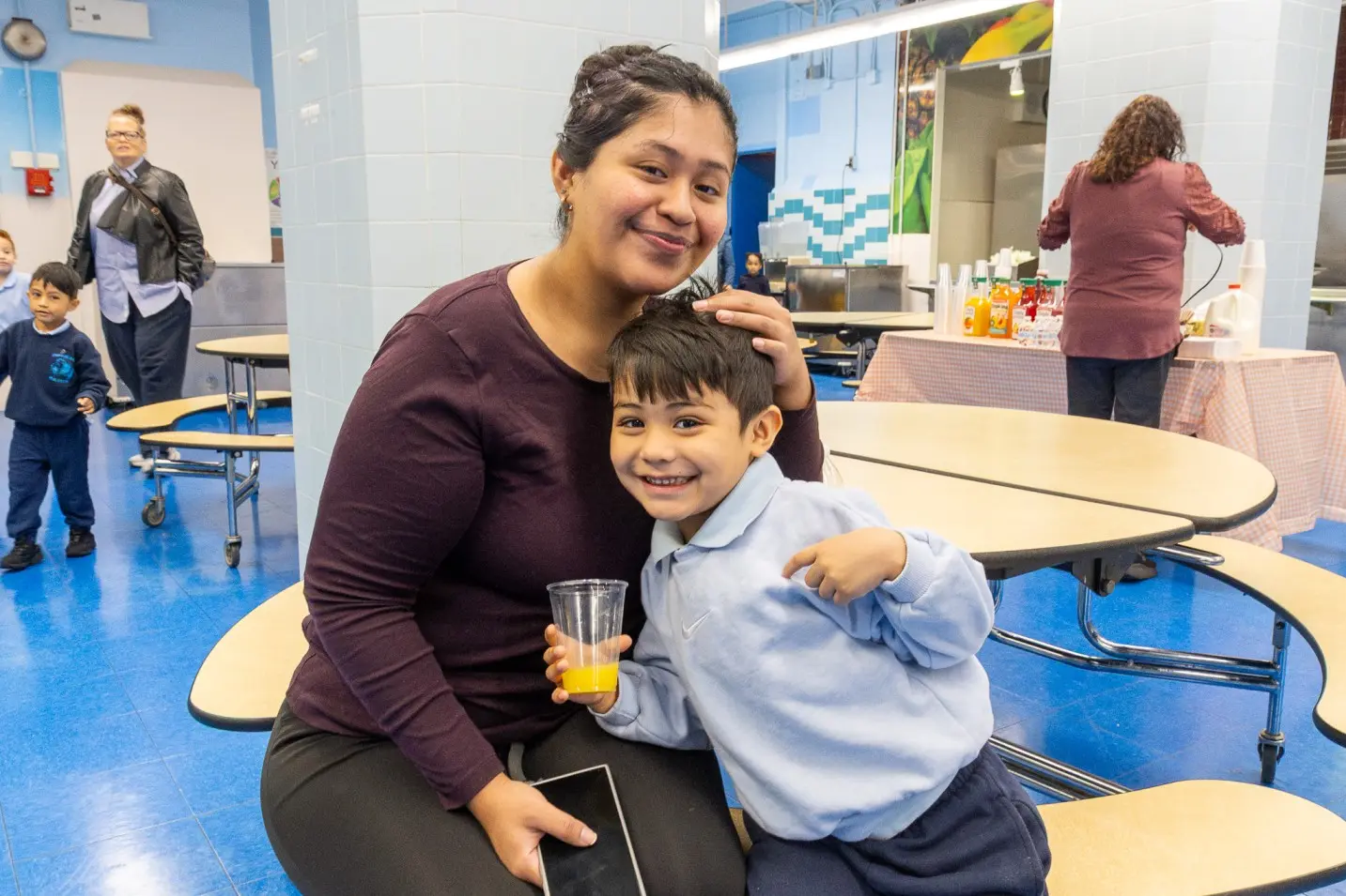 Parent and young student smiling together in school cafeteria