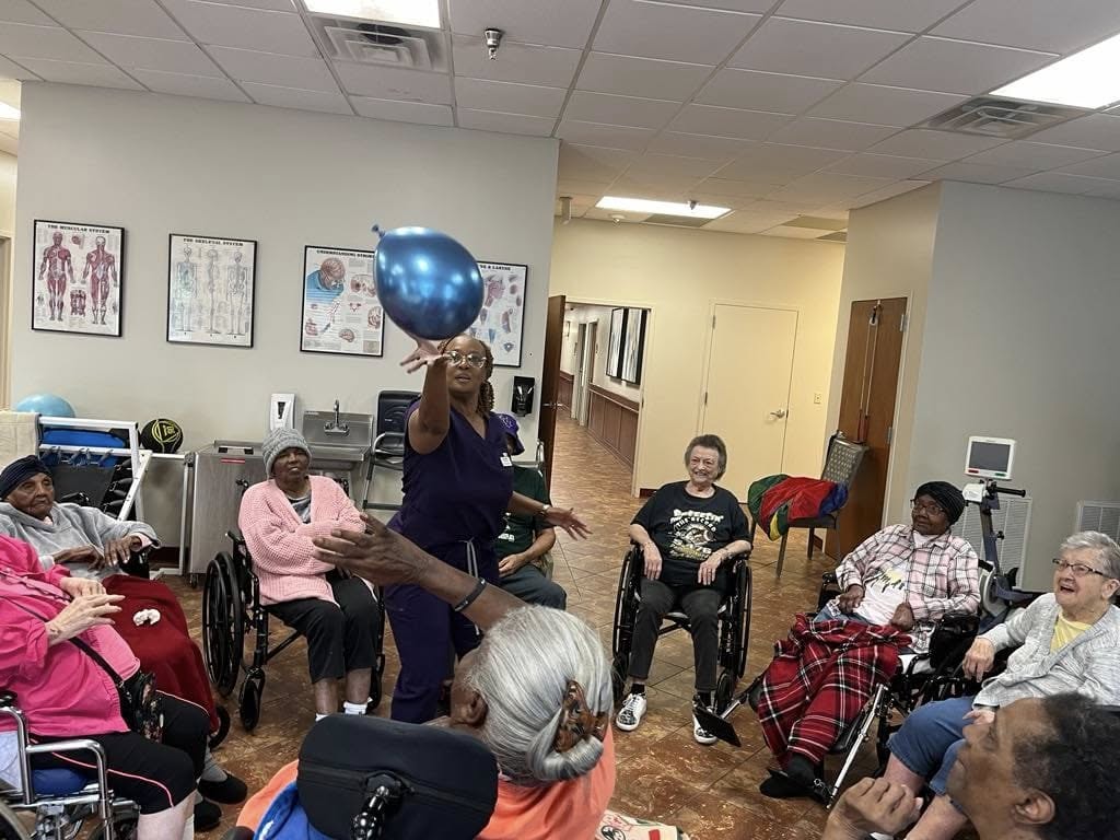 Nurse playing fun balloon game with residents