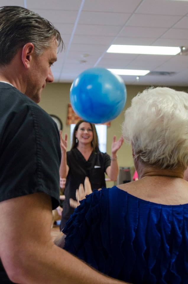 Two nurses playing balloon game with a resident