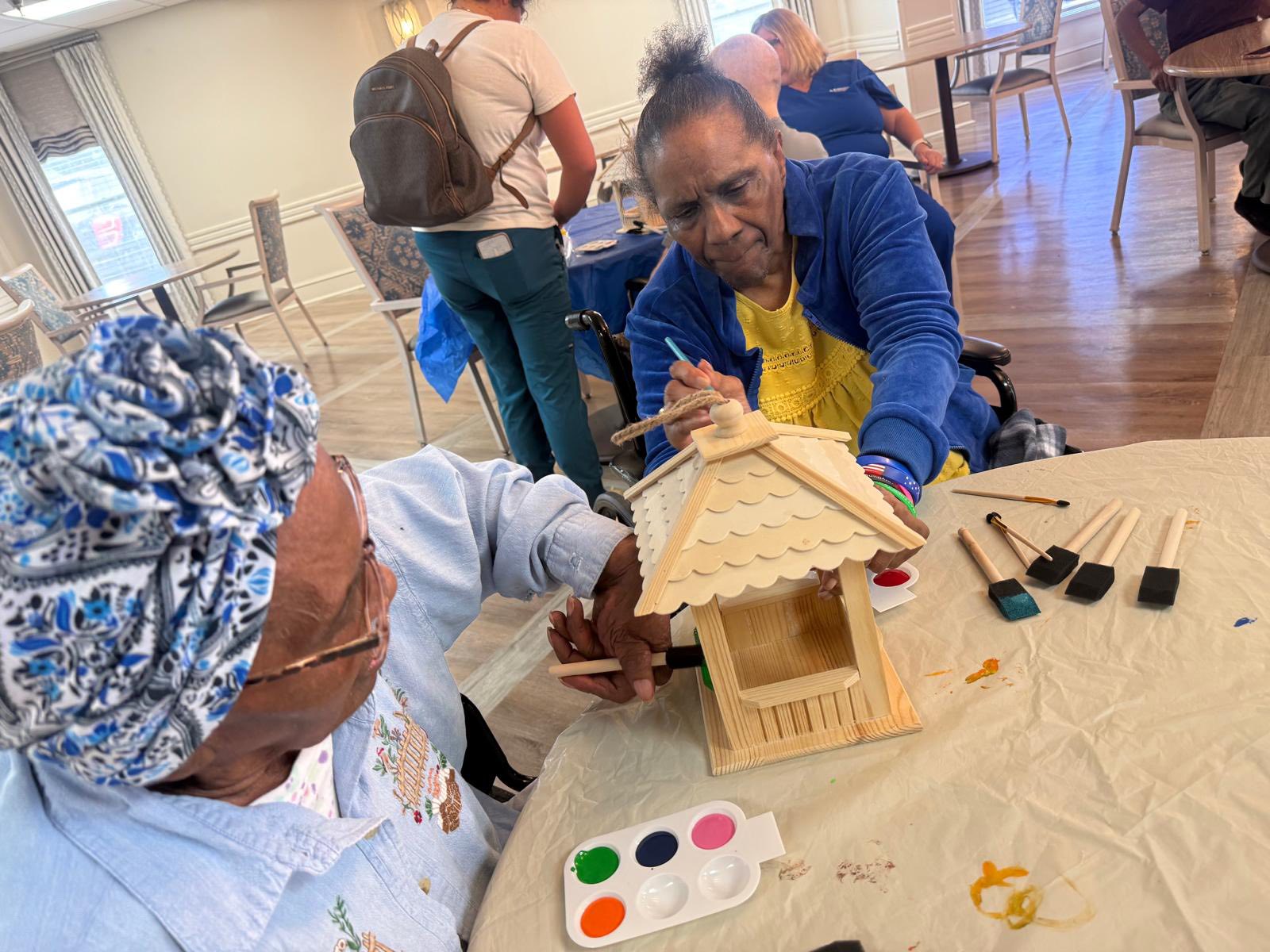 Two residents making a craft house out of popsicle sticks
