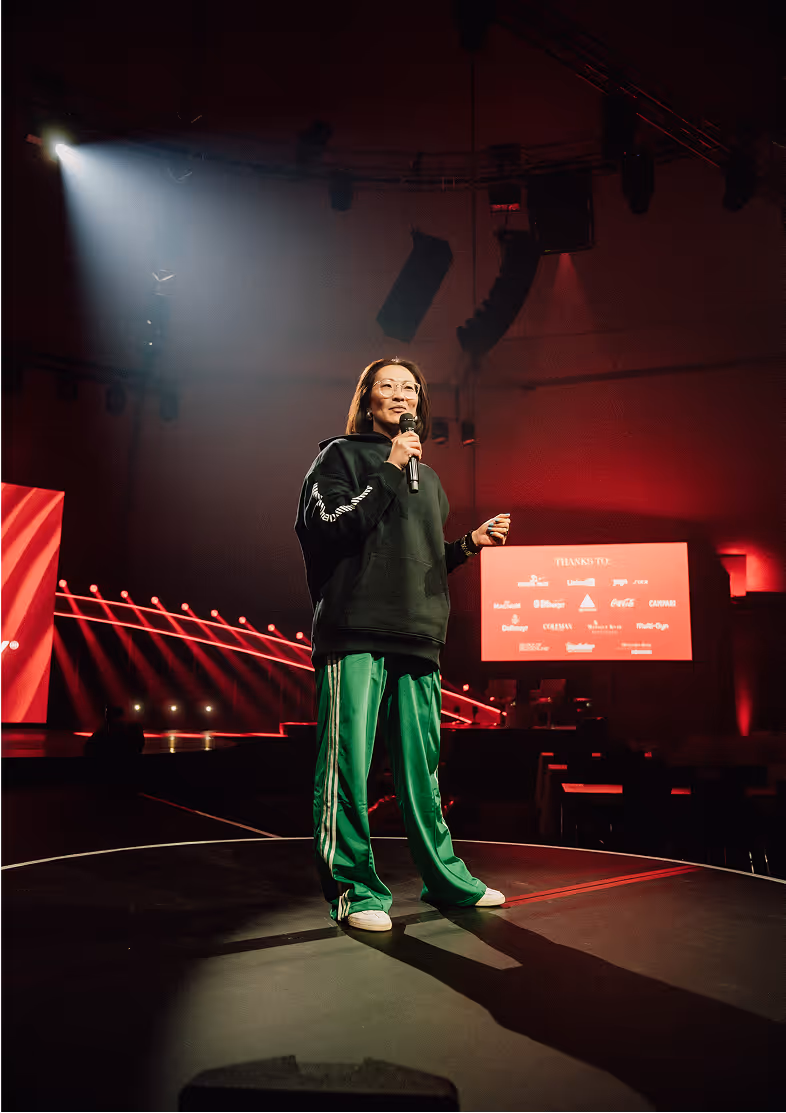 Lu Zhang standing on a stage with a microphone in her hand giving a talk