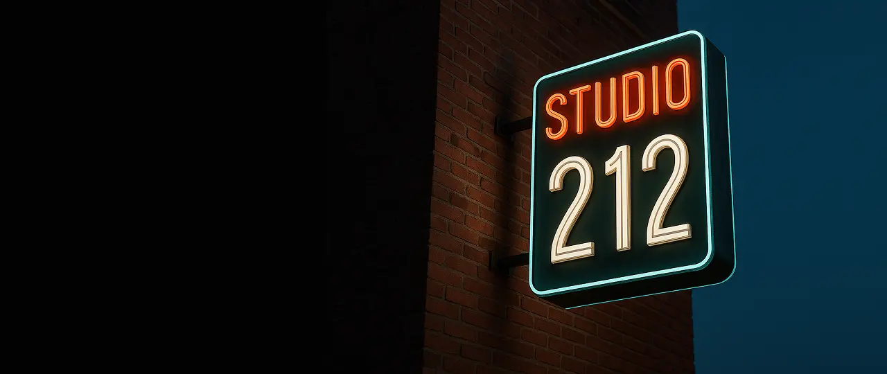 A neon sign with the words "Studio 212" hanging on a brick wall.