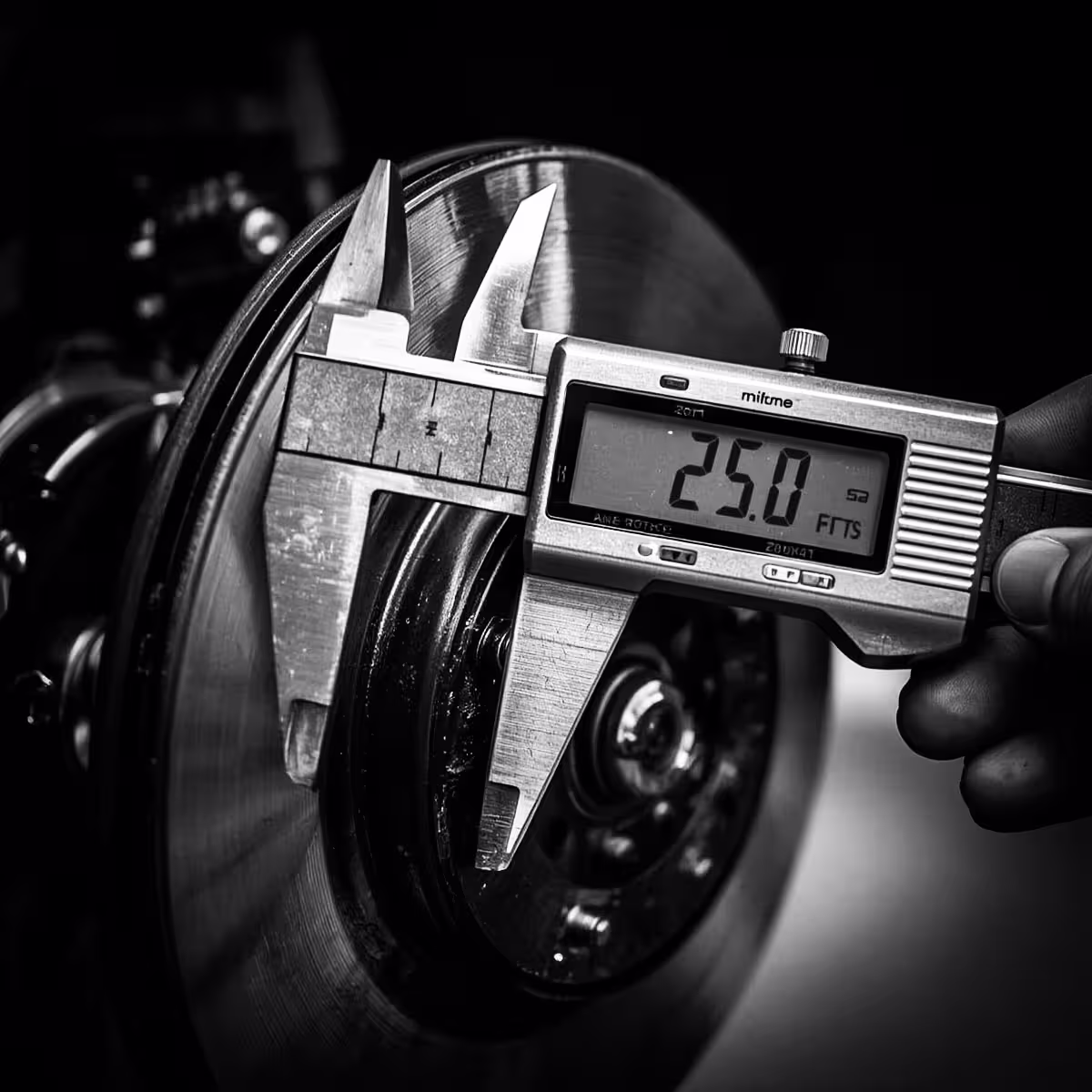 Macro close-up of a digital caliper measuring brake rotor thickness
