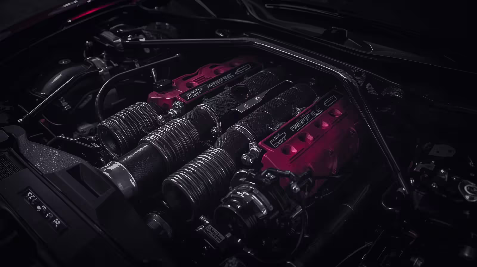 Detailed view of Ferrari V12 engine showing red intake manifolds, exposed hardware, and performance components