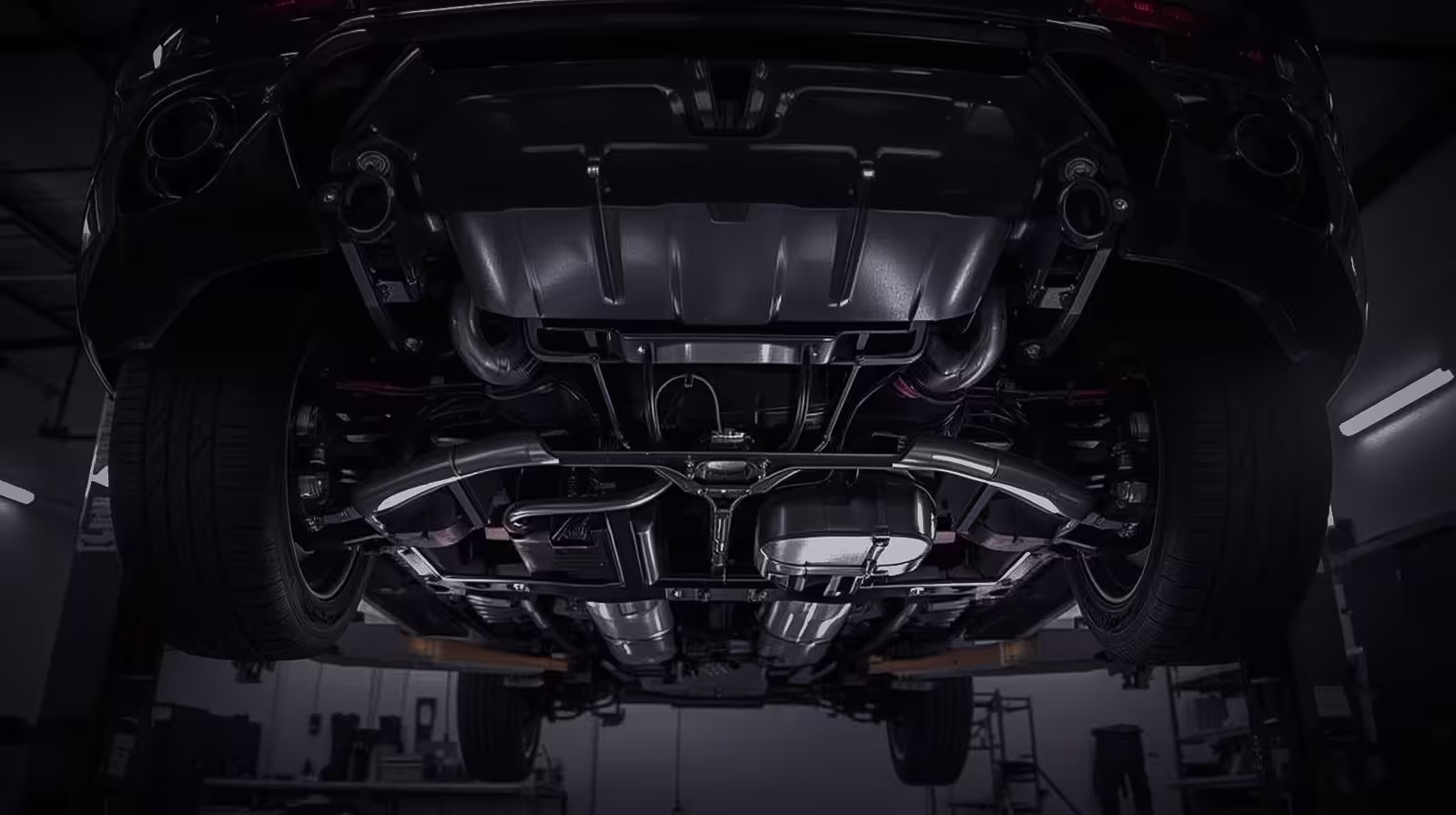 Undercarriage of a luxury European SUV on a lift, showing clean suspension and dual exhaust setup