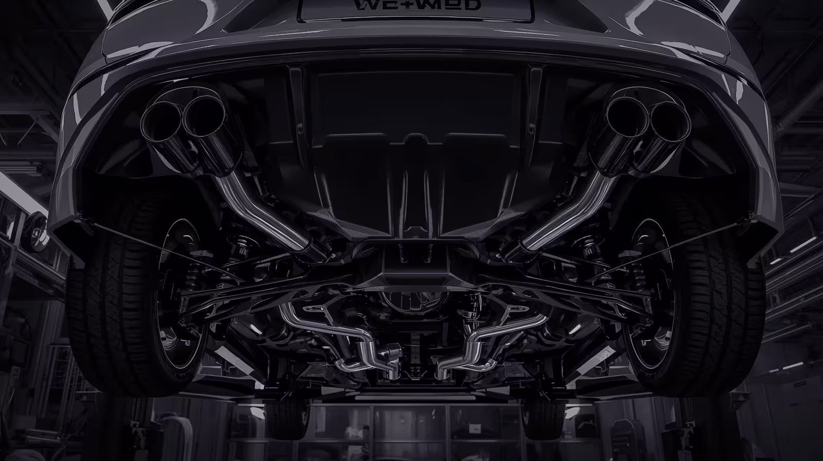 Undercarriage of Volkswagen on lift, showing MQB chassis suspension and dual exhaust routing in a modern garage