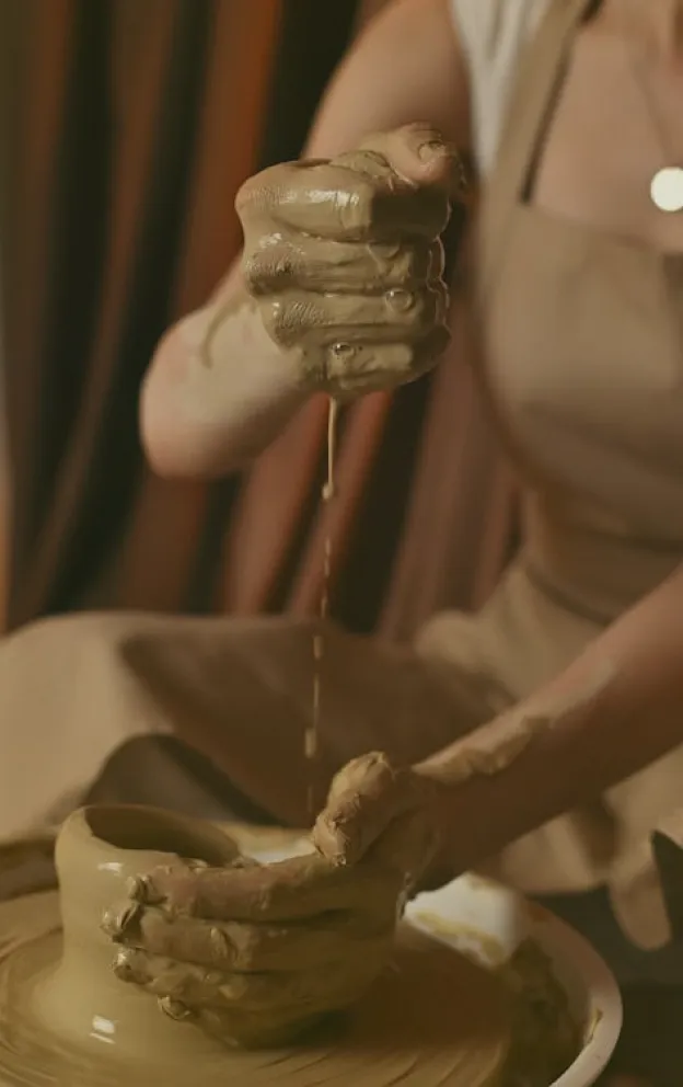 A close-up of an artist shaping clay on a pottery wheel, representing the arts and cultural sector.