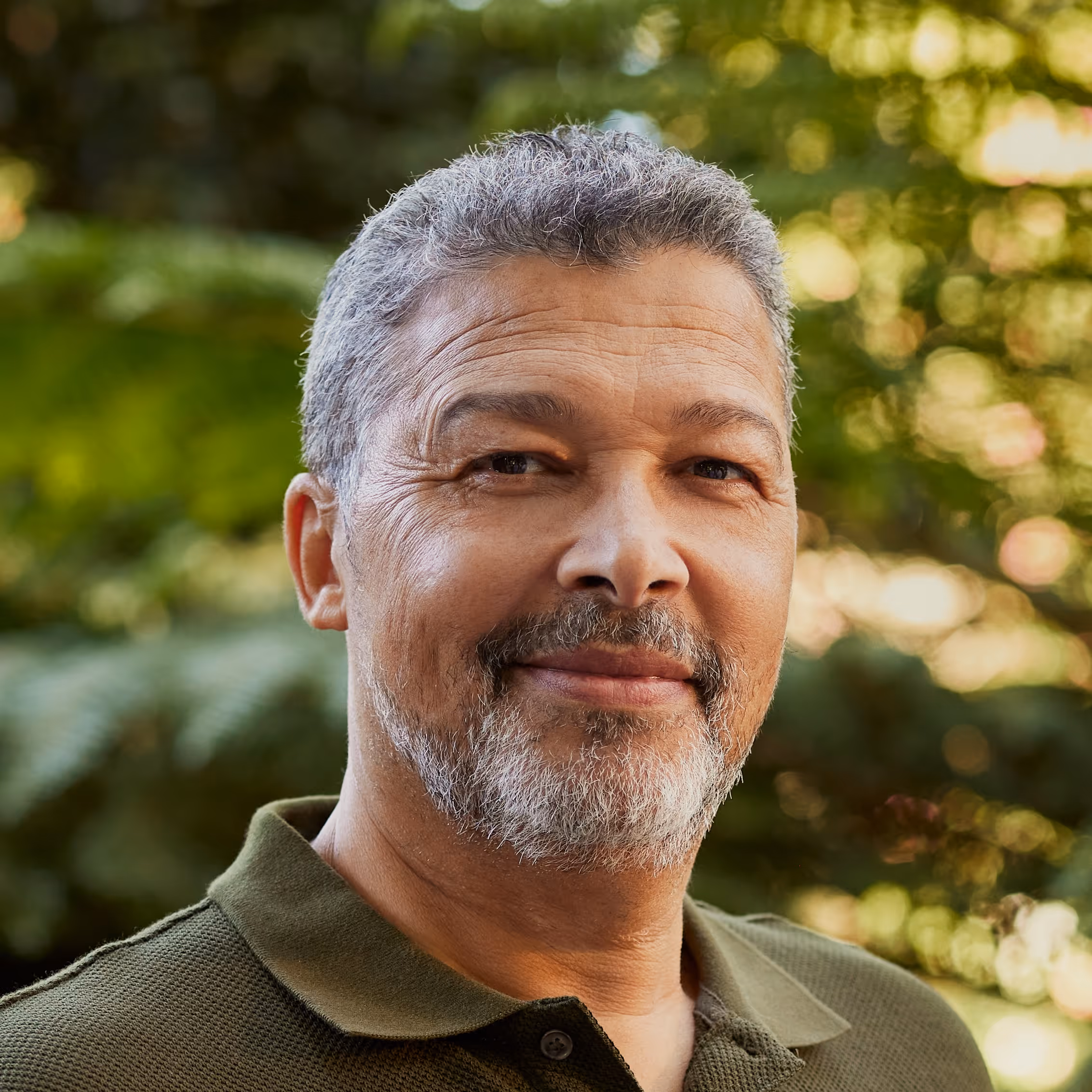 Middle-aged man with gray hair and beard smiling outdoors