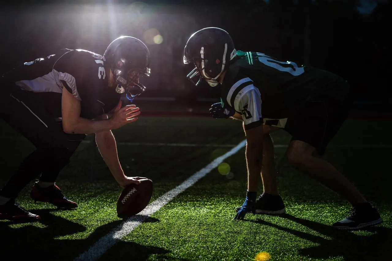Football players in full gear kneeling on the scrimmage line, preparing to snap the ball.