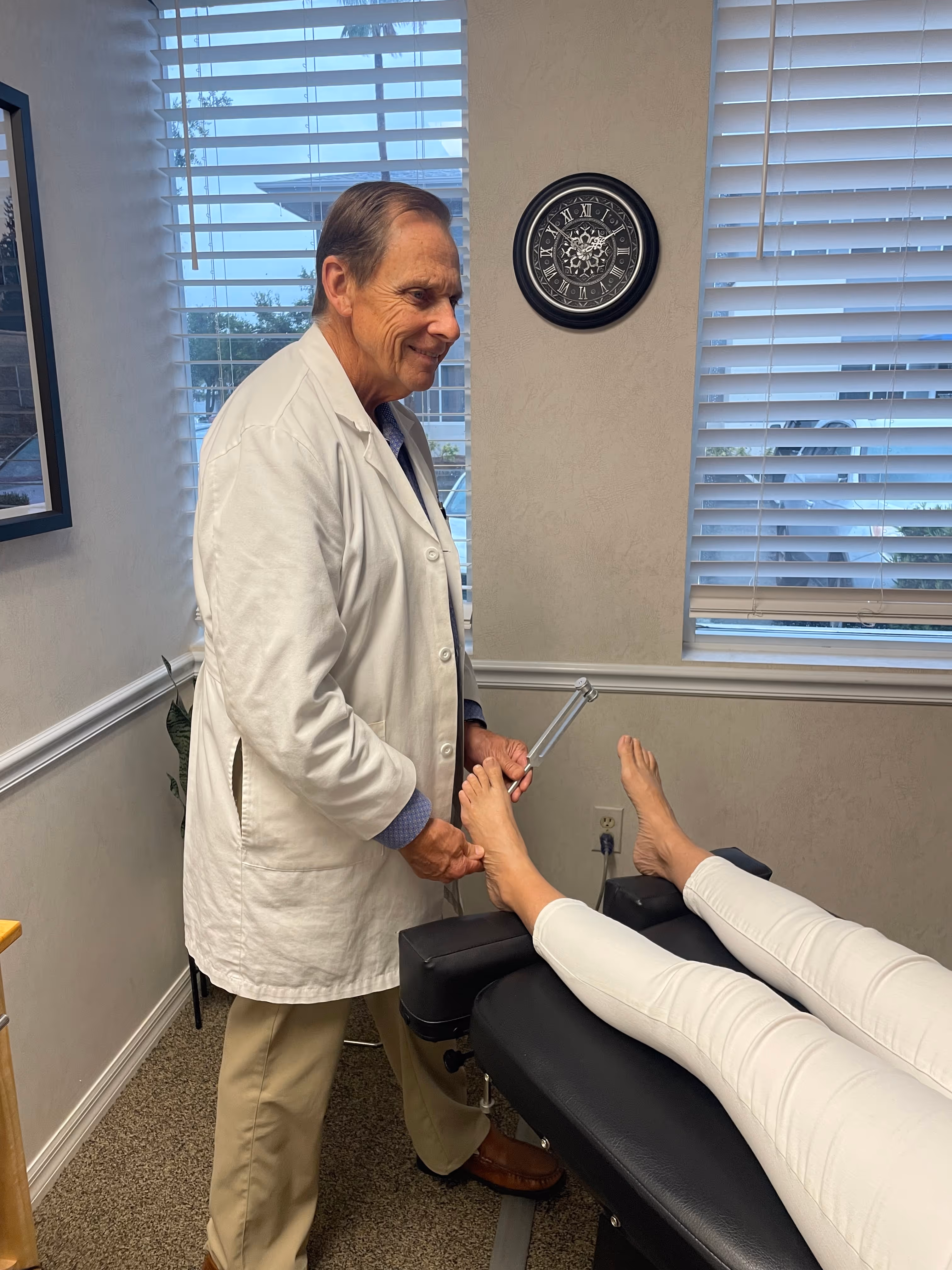 Dr. Kenneth Carle performing a neuropathy treatment on a patient's feet that is laying down.