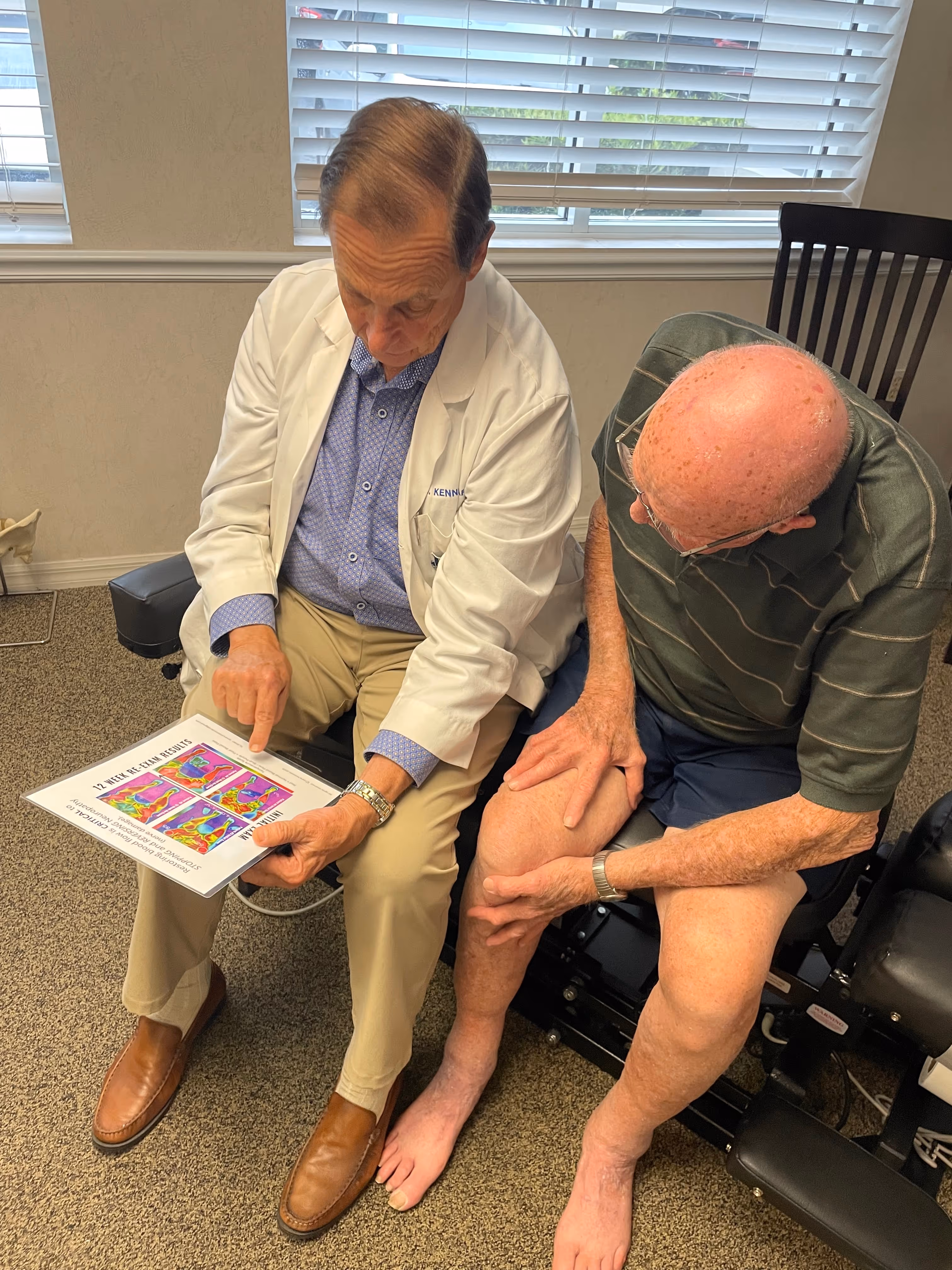 Dr. Carle sits with an elderly patient as he explains a neuropathy chart while sitting next to each other.