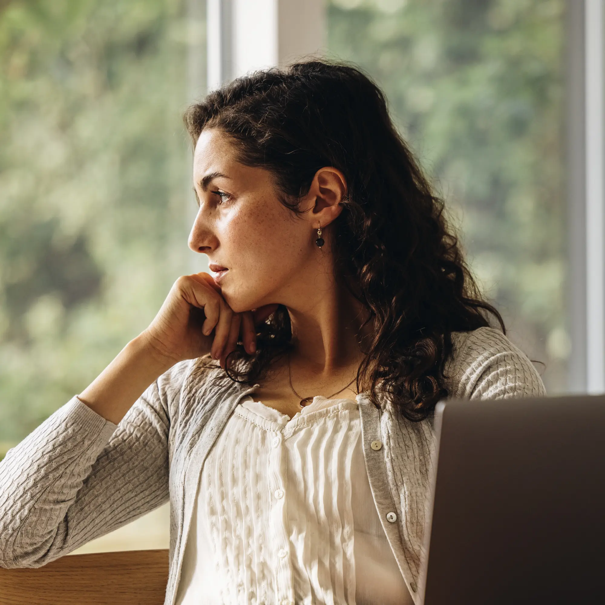 A woman looking into the distance with a laptop.
