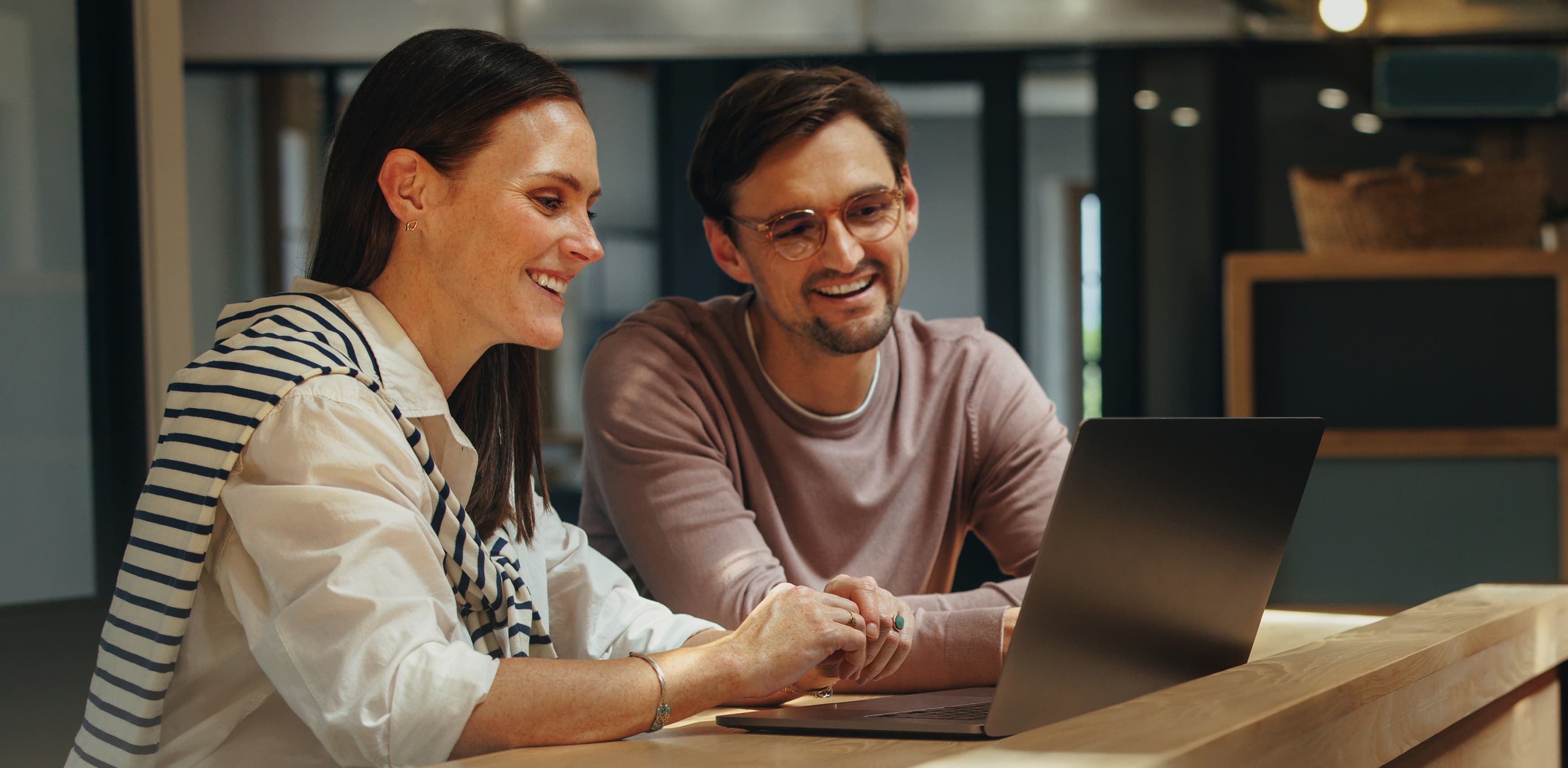 A smiling woman and man looking to a Laptop.