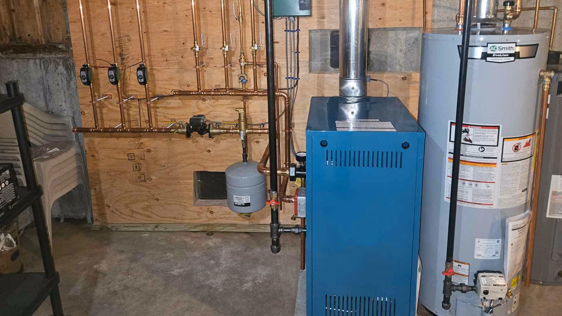 High-efficiency residential boiler and AO Smith water heater professionally installed by Minuteman Plumbing & Heating, featuring clean copper piping and expansion tank setup.