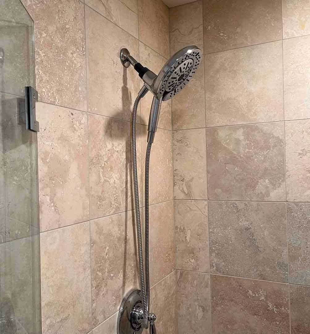 Modern tiled shower with chrome handheld showerhead and adjustable spray settings, installed by Minuteman Plumbing for enhanced comfort and functionality.