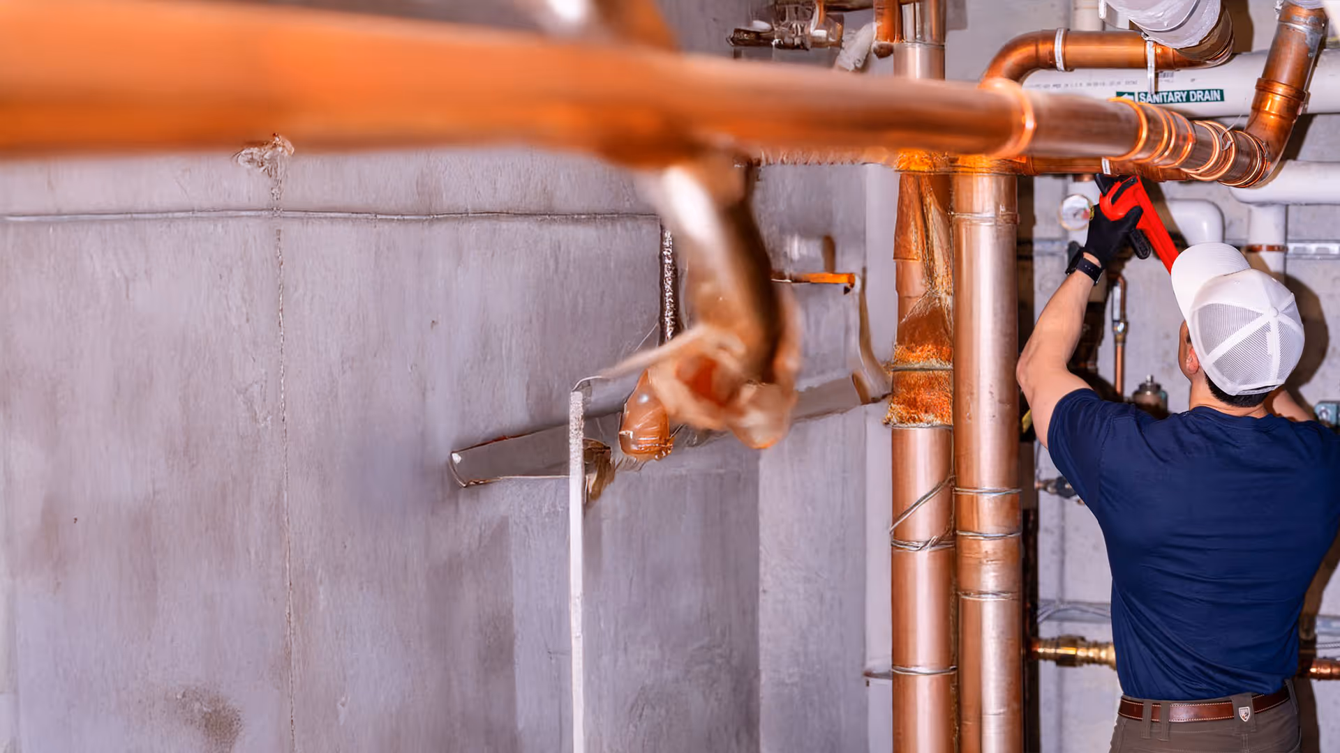 Minuteman Plumbing, Heating & Cooling technician repairing copper pipes in a basement, performing professional plumbing maintenance to ensure safe and efficient water flow.