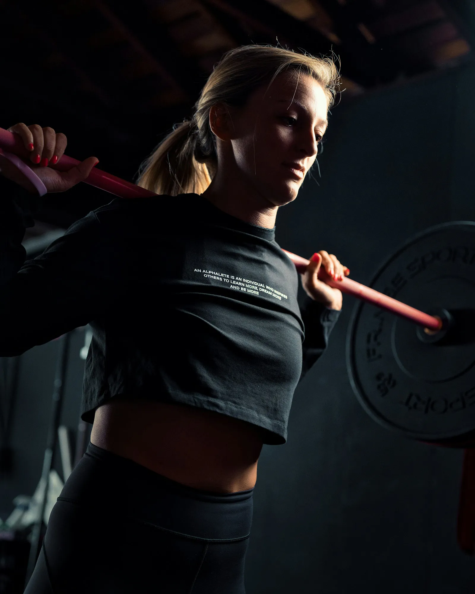 A young woman lifting weights in a gym.