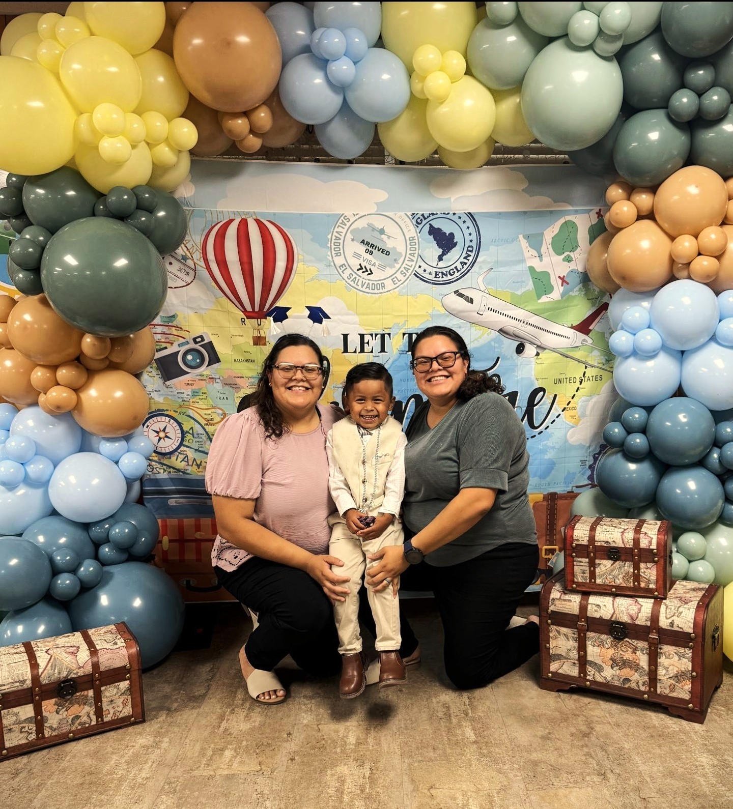 two teachers on each side of a preschooler smiling during graduation