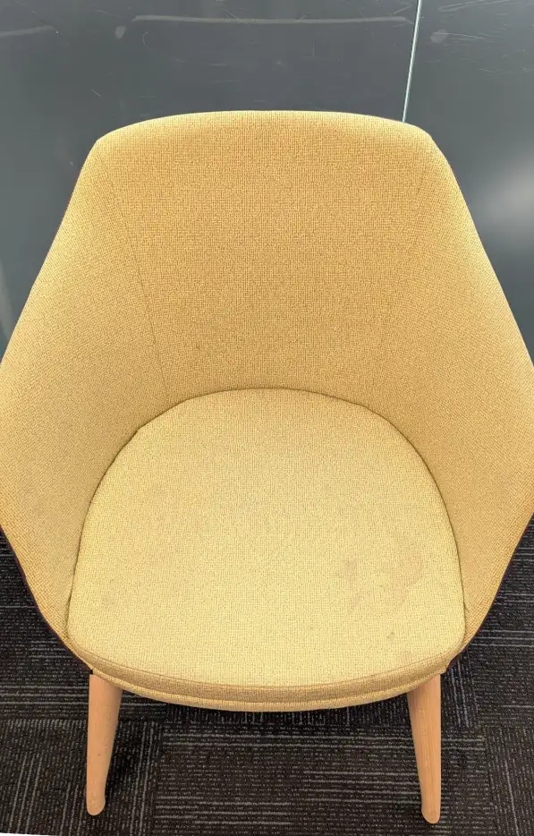 Yellow fabric chair before cleaning, showing visible dirt and dull fabric.