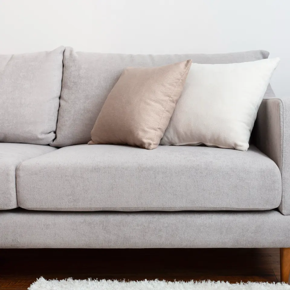Light grey fabric lounge with neutral cushions against a white wall.