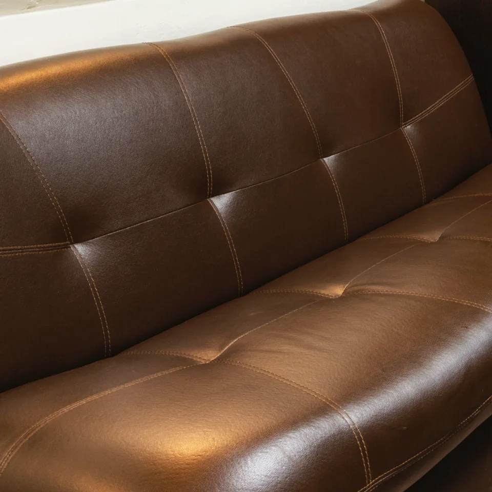 Close-up of a dark brown leather lounge with stitched cushions.