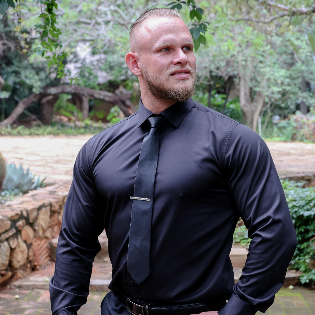 Smiling woman with shoulder-length brown hair wearing a black blazer and gold necklace against a dark background.