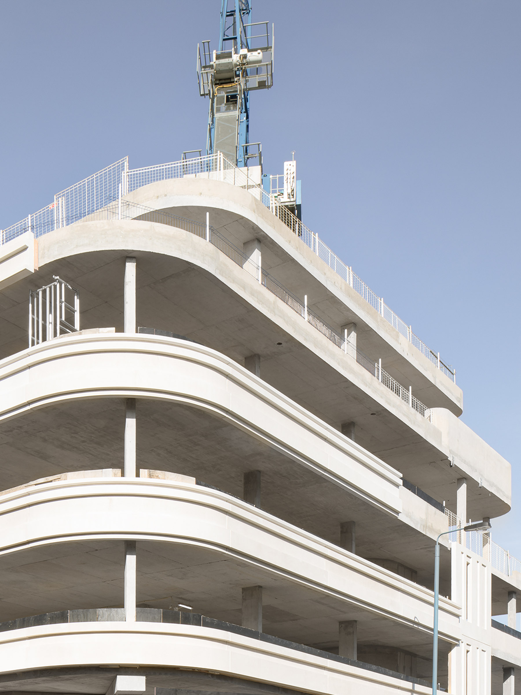 Mid-construction photograph showing structural slabs and precast facade panels forming the curved geometry.