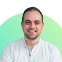 Headshot of smiling man with beard wearing light blue shirt against green background