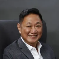 Professional headshot of an Asian man smiling, wearing dark blazer and white shirt