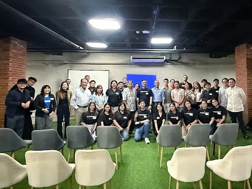 Large diverse group of people posing together in modern office space with green flooring