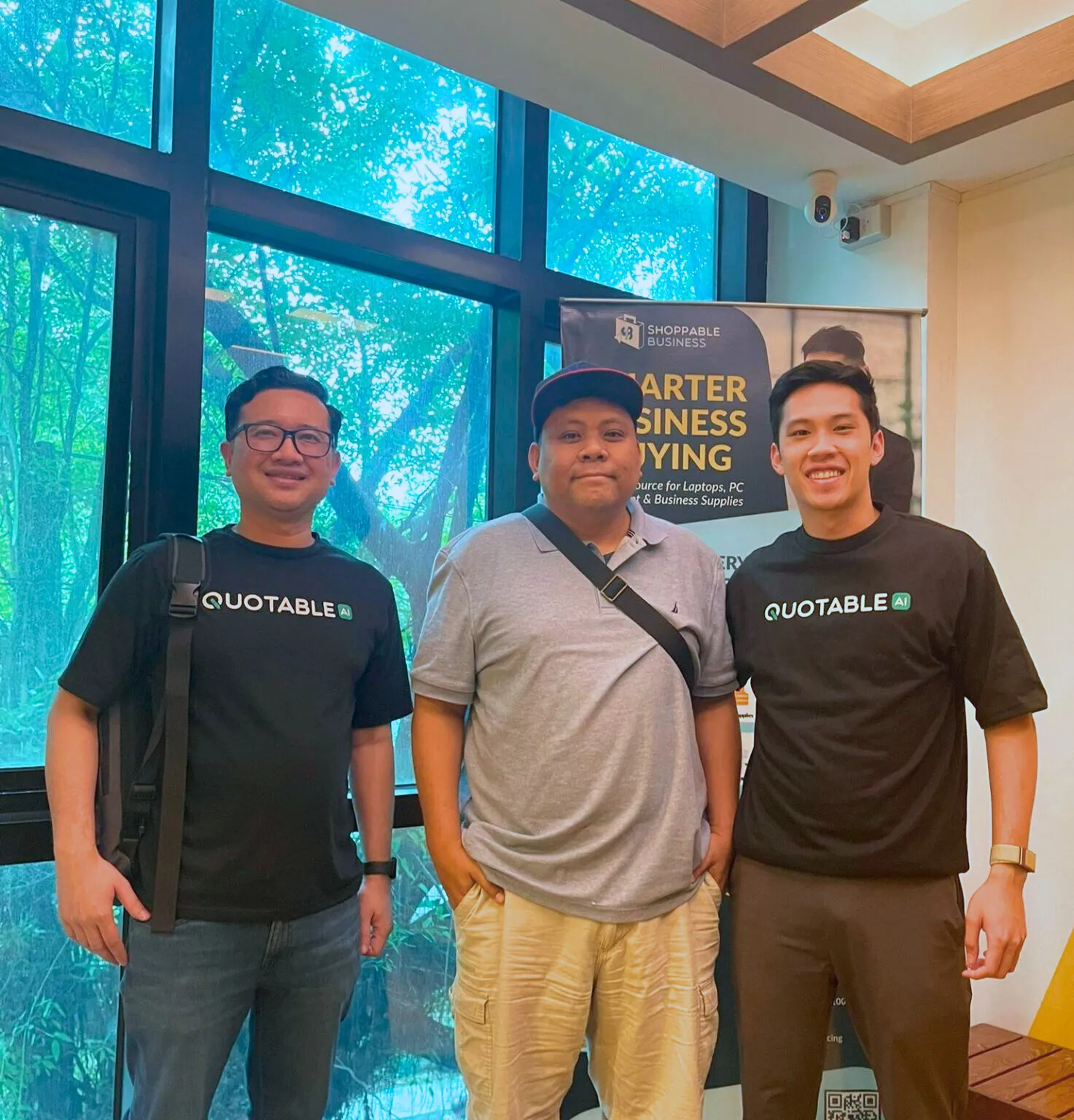Quotable AI team posing in office with turquoise window display.