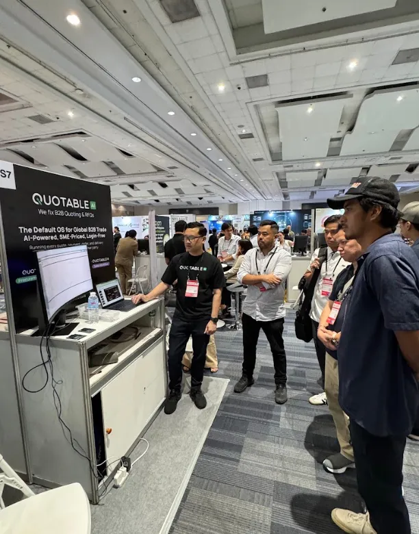 Conference attendees with ID badges gather around a Quotable AI technology booth display.