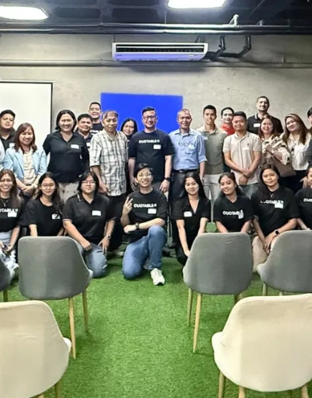 Group photo of Quotable AI team members and customers posing together in modern office space with green flooring