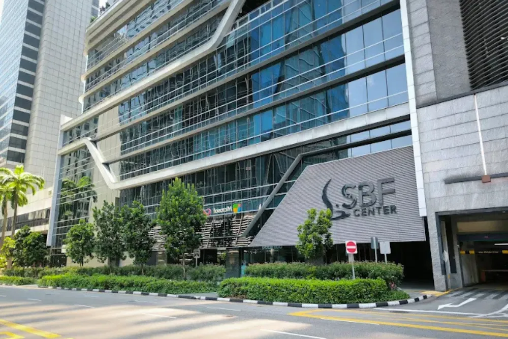 Modern SBF Center building with glass facade, green landscaping, and tropical plants