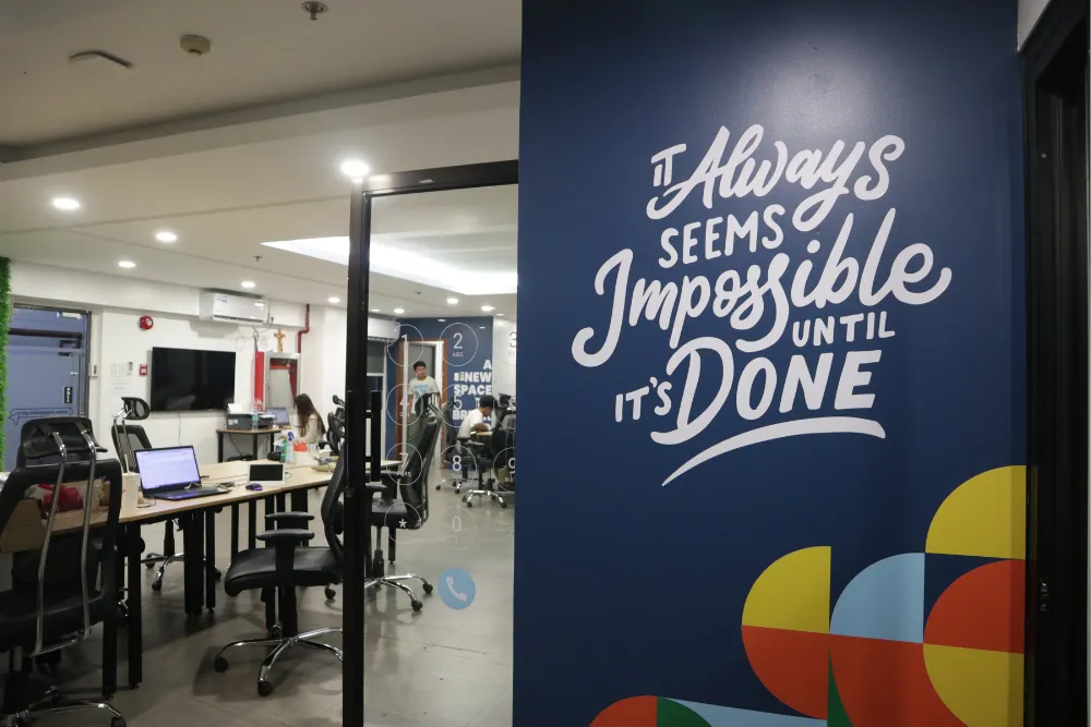 Quotable AI office space with motivational quote wall: "It Always Seems Impossible Until It's Done"