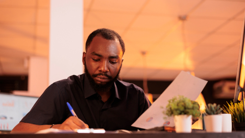 Accounts payable specialist reviewing a supplier invoice at a desk in the evening.
