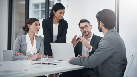 Finance team discussing payment platform costs around a conference table.