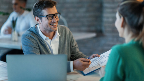 Banker in glasses reviewing an international business bank account statement with a client.