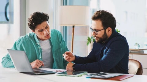 Two colleagues comparing quote-to-cash software options on a laptop and tablet.