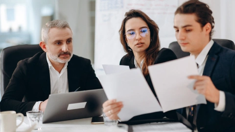 Team members review and discuss printed reports around a meeting table