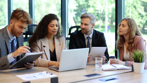 Four colleagues in business attire discussing options at a table.