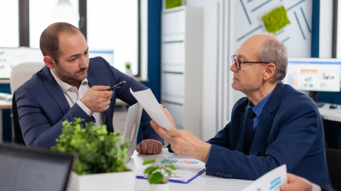 Two businessmen in a focused discussion over documents.