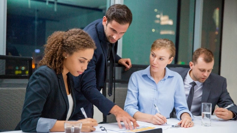 Business team reviews and signs regulatory paperwork at a conference table