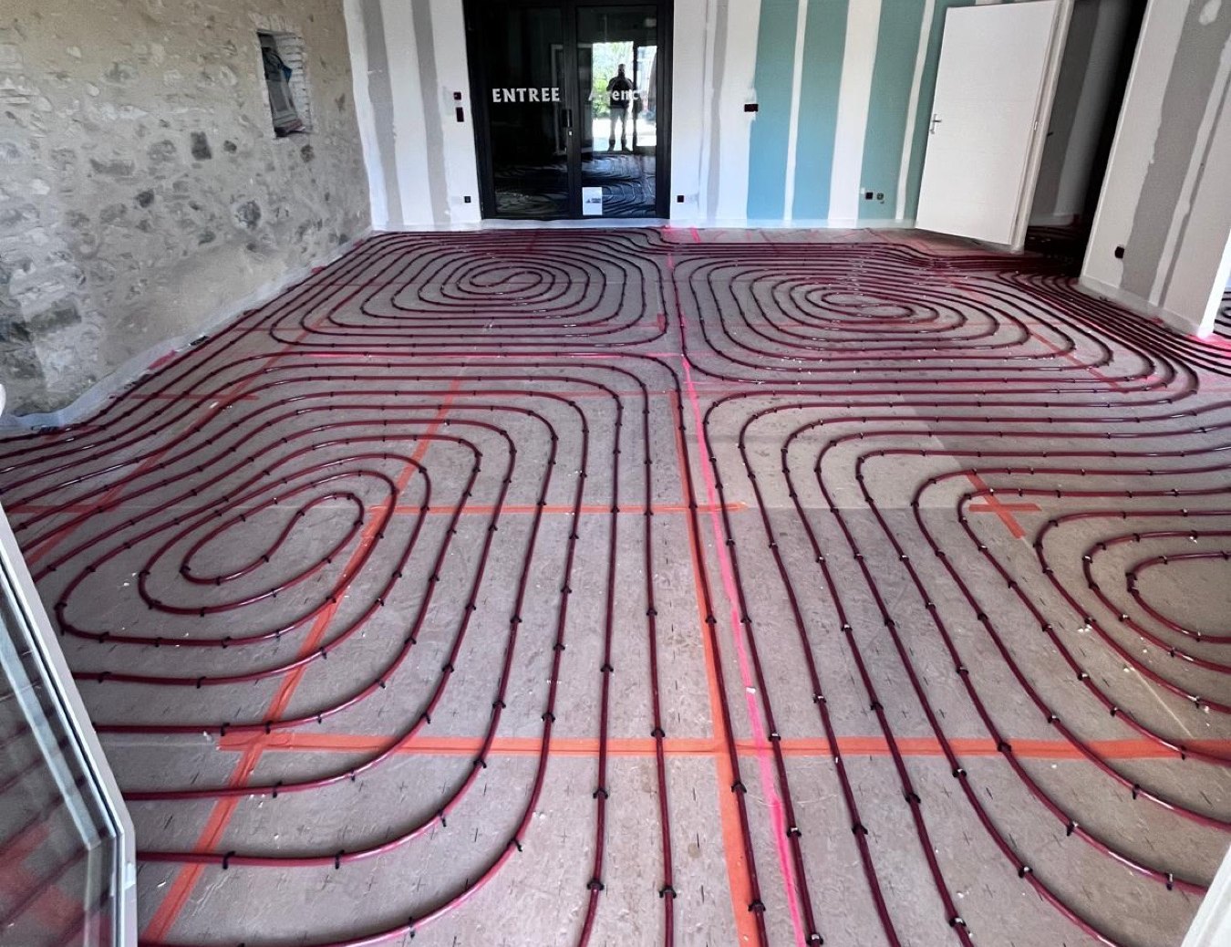 Entrée en pierres apparentes avec les boucles de plancher chauffant posées avant la chape